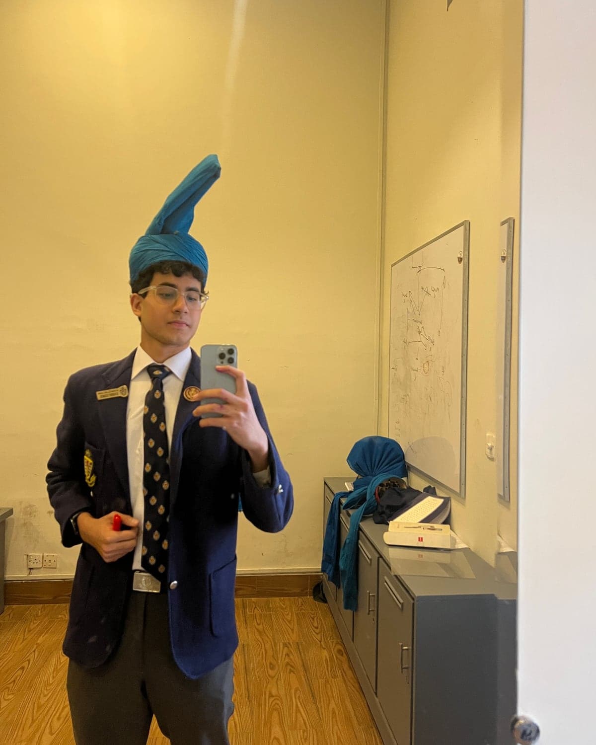 Hamza Rahim in a school blazer and tie, wearing a blue turban, taking a mirror selfie